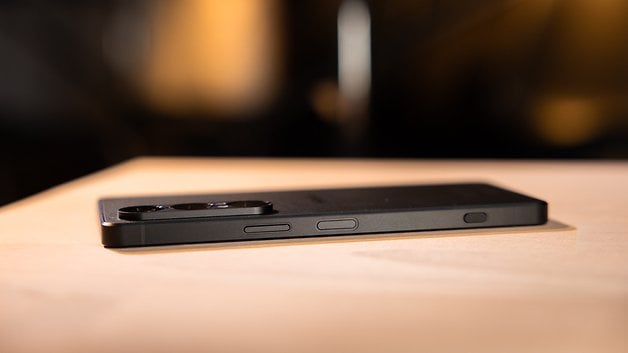 A Sony Xperia 1 VIII smartphone lying on a wooden surface, showing its side buttons and camera lenses.