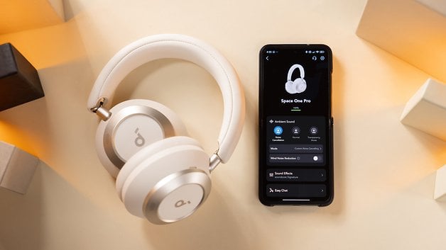 Casque blanc Anker Soundcore Space One à côté d'un smartphone affichant l'interface de l'application.