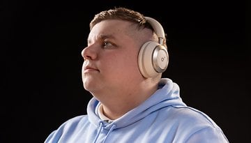 A person wearing Anker Soundcore Space One headphones, looking thoughtfully upwards against a dark background.