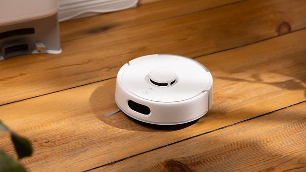 A white robot vacuum cleaner on a wooden floor, marked as the SwitchBot K10 Pro.