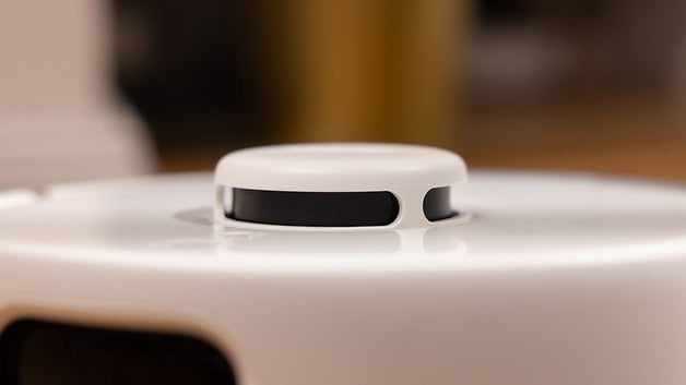 A close-up of the SwitchBot K10 Pro device, showing its top surface and a round button.