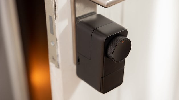 Ein SwitchBot Lock Pro Smart-Lock, das an einer Tür befestigt ist, mit einem schwarzen Design und einem drehbaren Knopf.