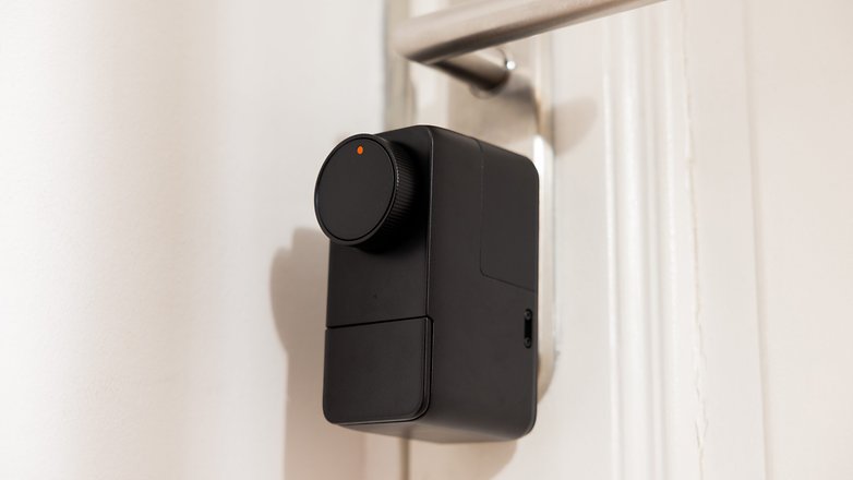 Ein schwarzes SwitchBot Lock Pro, das an einer Tür montiert ist, mit einem runden Drehknopf und einer kleinen Anzeigeleuchte.