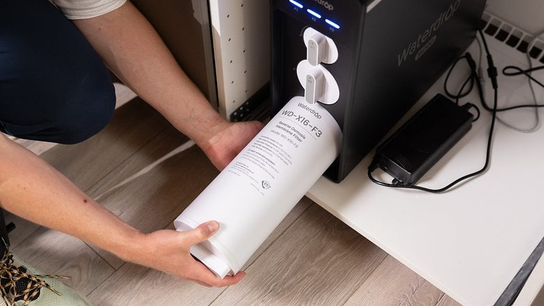 Eine Person installiert einen Waterdrop WD-X16-F3-Filter in ein schwarzes Wasserfiltersystem.