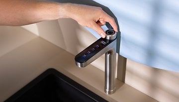 Eine Hand passt einen modernen Küchenwasserhahn mit Touch-Bedienelementen und elegantem Design an.