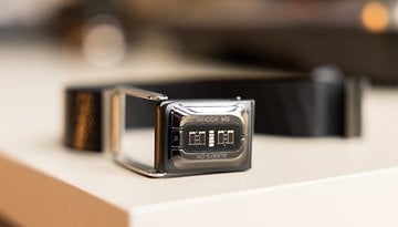 A black wearable device with a display showing 'WHOOP MG' lying on a flat surface.