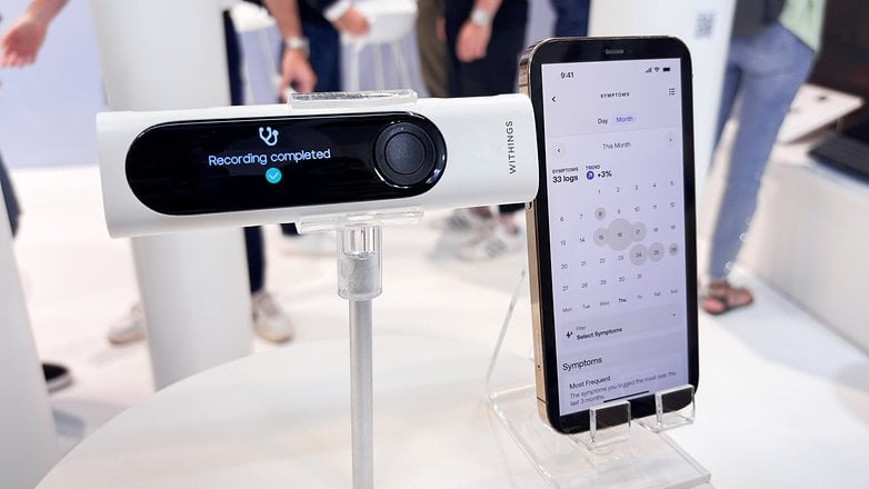 Withings BeamO al lado de un teléfono que muestra la interfaz de usuario de la aplicación complementaria en un teléfono