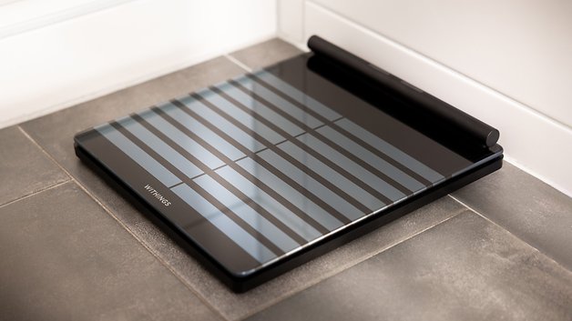 A Withings Body Scan smart scale placed on a tiled floor.