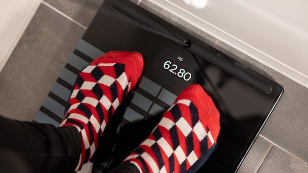 A person standing on a Withings Body Scan scale displaying 62.80 kg.