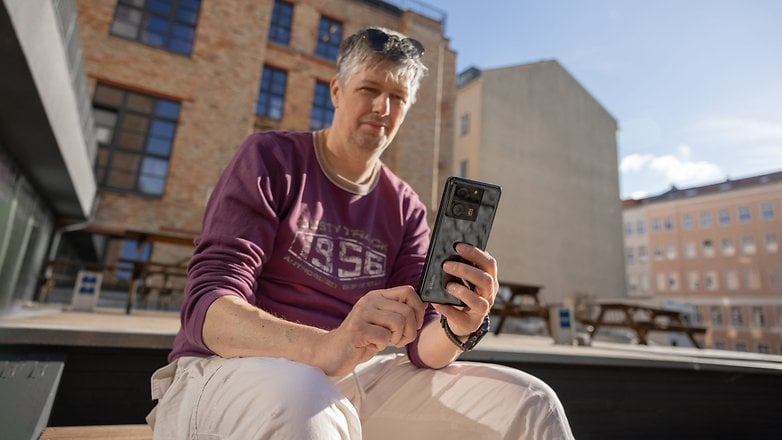 Matt assis dehors tenant le Xiaomi 13T dans sa main