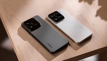 Two Xiaomi 15 smartphones, one gray and one white, resting on a wooden surface.