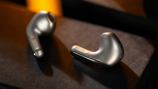 Deux écouteurs sans fil Xiaomi Buds 5 reposant sur une surface sombre.