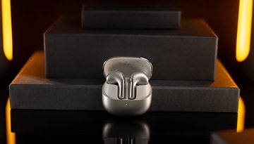 Xiaomi Buds 5 drahtlose Ohrhörer auf einer dunklen Oberfläche mit sanfter Beleuchtung.