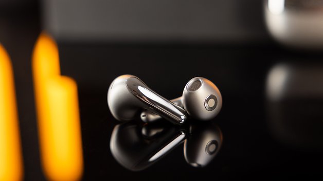 Écouteurs sans fil Xiaomi Buds 5 reposant sur une surface noire réfléchissante avec un éclairage doux.