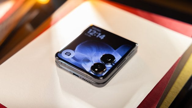 Ein Xiaomi Mix Flip-Smartphone, das auf einer Oberfläche liegt und auf dem Bildschirm die Uhrzeit 12