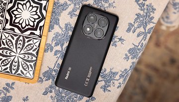 Black Xiaomi Redmi Note 14 Pro 5G smartphone on a floral-patterned tablecloth.