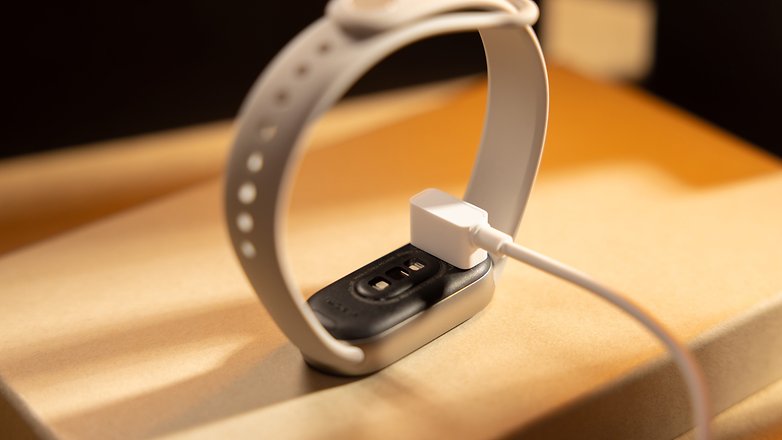 Un Xiaomi Smart Band 9 en charge sur une surface avec un connecteur USB.