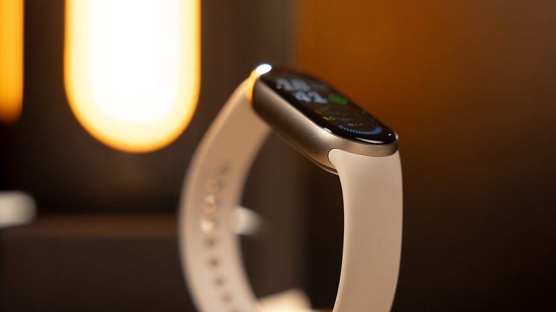 Gros plan d'une Xiaomi Smart Band 9 avec un bracelet blanc sur un fond doucement éclairé.