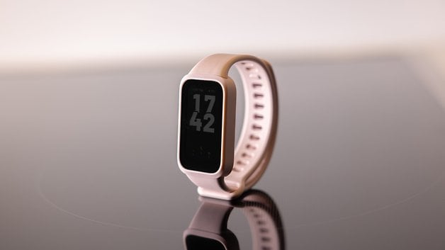 Eine Xiaomi Smart Band 9 Active, die auf einer reflektierenden Oberfläche mit der Uhrzeit 17:42 angezeigt wird.