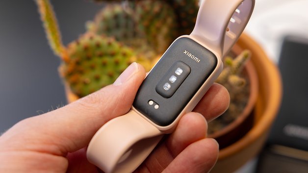 Eine Person hält ein Xiaomi Smart Band 9 Active, mit einem Kaktus im Hintergrund.