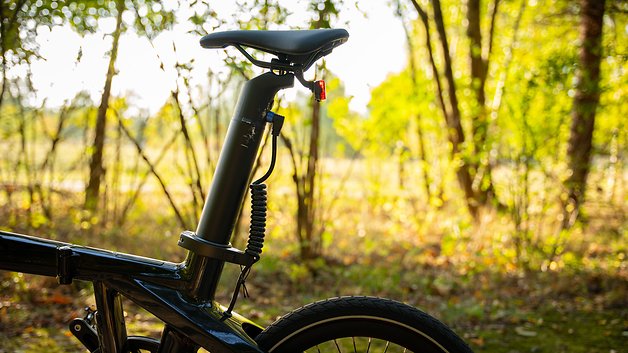 Nahaufnahme eines Fahrrad-Sattelrohrs in der Natur mit Sonnenlicht, das durch die Bäume filtert.