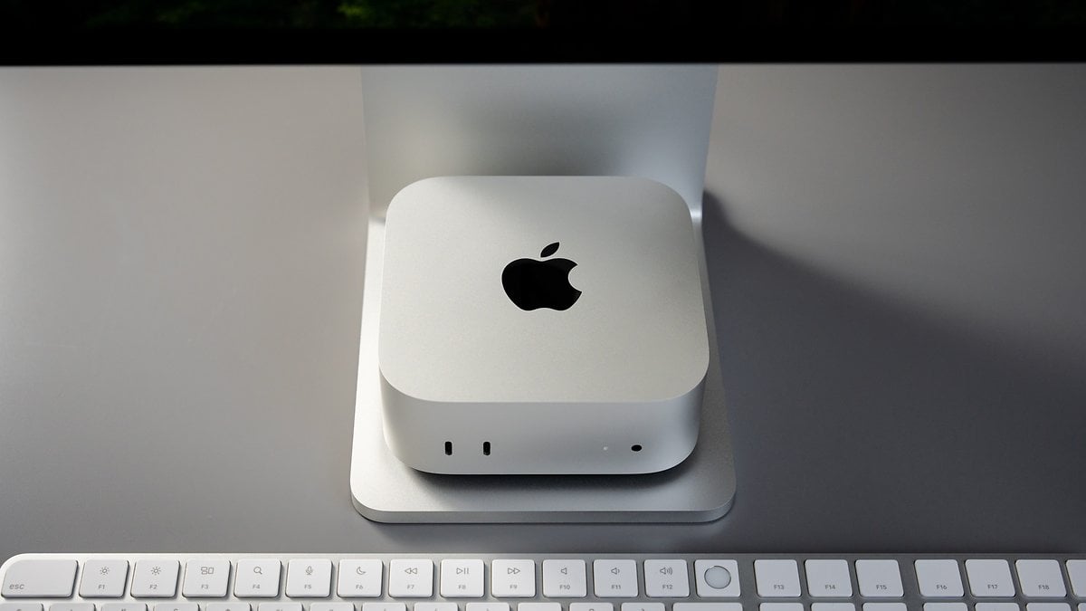 A silver Apple Mac Mini M4 Pro on a stand, with a keyboard in the foreground.