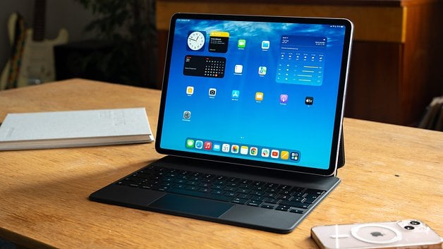 iPad Air 2024 em uma mesa de madeira com teclado, mostrando uma tela inicial azul.