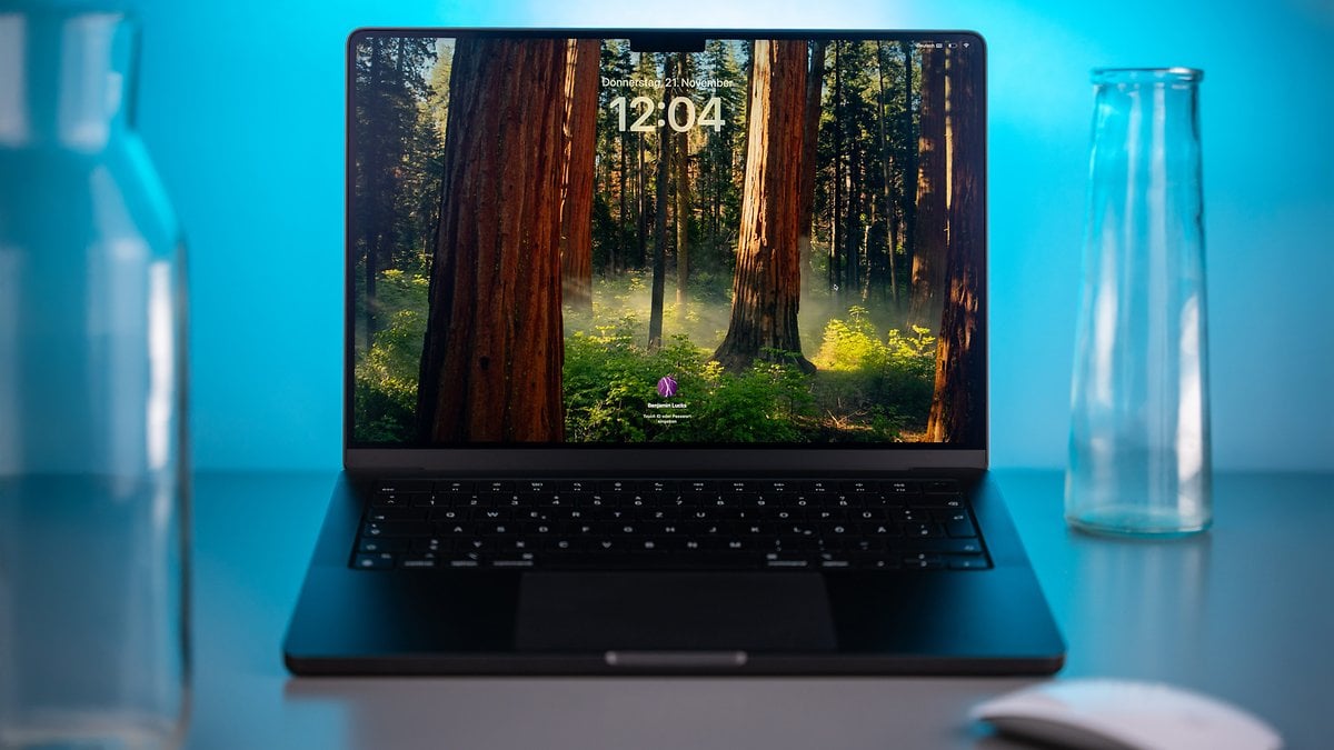 Apple MacBook Pro M4 avec un fond d'écran de forêt affichant l'heure 12:04.