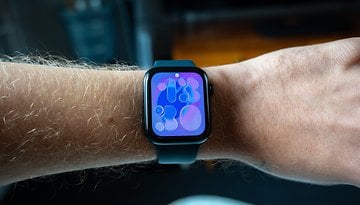 A close-up of an Apple Watch SE 3 on a wrist displaying a colorful abstract watch face.