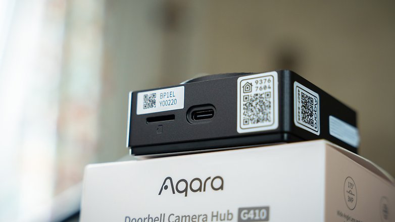 Aqara Türbell-Kamera-Hub G410 mit sichtbaren Etiketten und Anschlüssen vor unscharfem Hintergrund. Aqara Türbell-Kamera-Hub G410 mit sichtbaren Etiketten und Anschlüssen vor unscharfem Hintergrund.