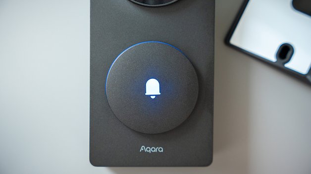 Aqara Türklingelkamera-Hub mit einem blauen, beleuchteten Glockensymbol.