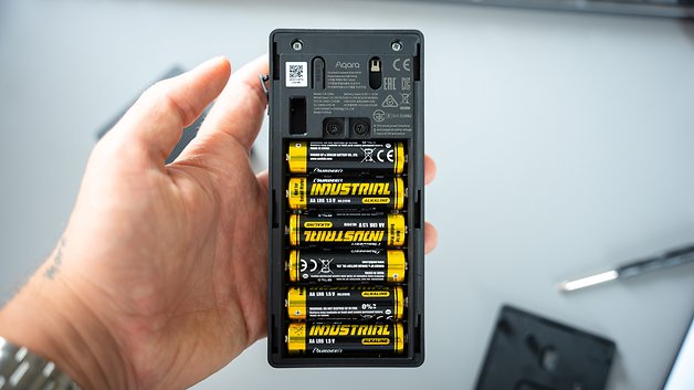 Eine Hand hält das Aqara-Türklingel-Kamerahub mit installierten Batterien.