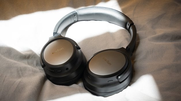 A pair of black EarFun Tune Pro headphones lies on a grey surface.