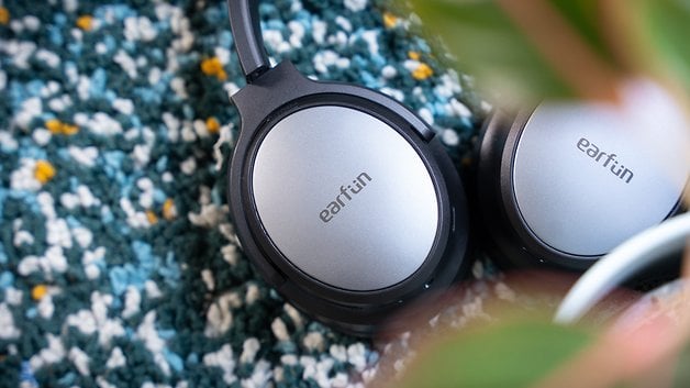 Close-up of the EarFun Tune Pro headphones on a textured surface with a plant in the foreground.