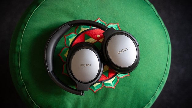 Black and silver Earfun Tune Pro headphones on a green decorative pillow.