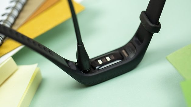 A close-up of a Garmin Vivosmart 5 fitness tracker with a charging cable attached.