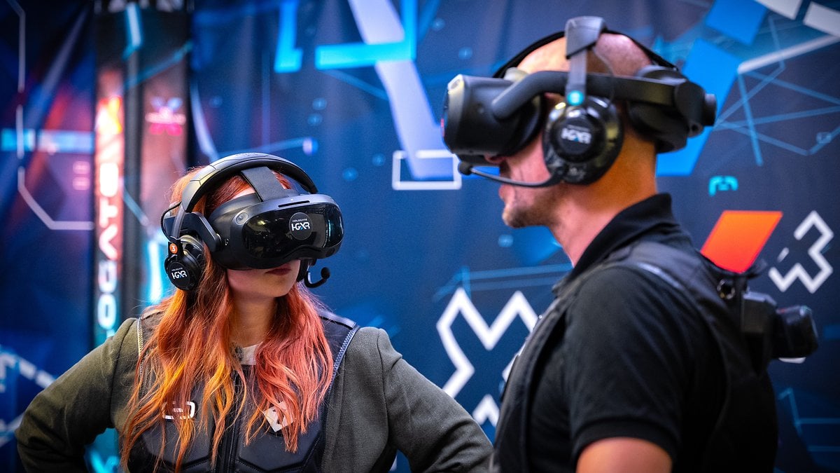 Deux personnes portant des casques de réalité virtuelle s'engagent dans une expérience de réalité virtuelle sur fond numérique.