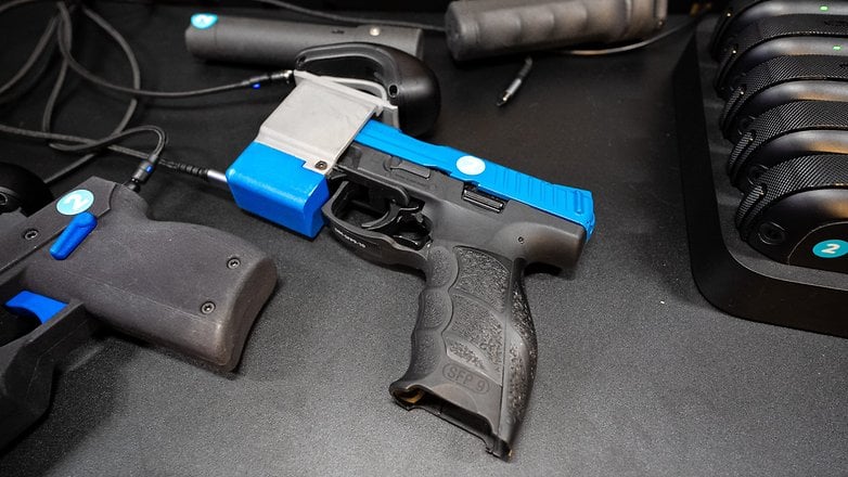 A blue and black handgun with electronic components, surrounded by gaming equipment.