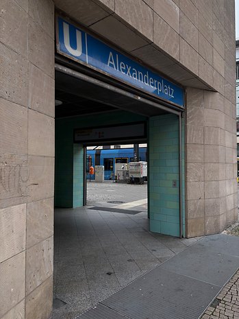 Eingang zur U-Bahn-Station Alexanderplatz mit gefliesten Wänden und Beschilderung.