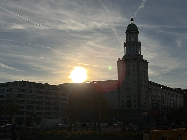 Silhouette eines Gebäudes mit grüner Kuppel und Sonnenuntergang im Hintergrund.