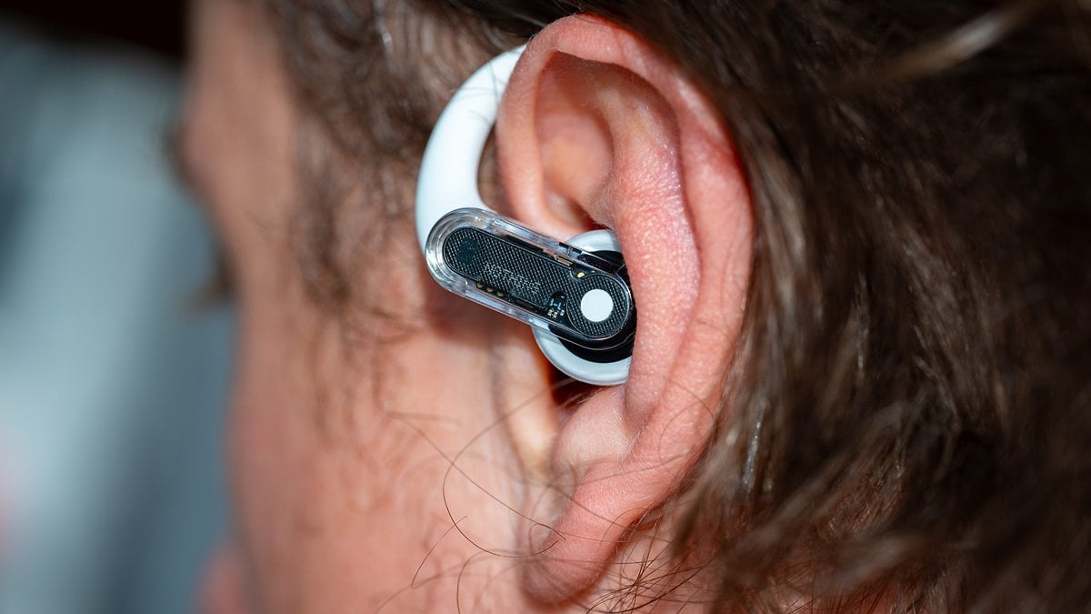 Gros plan d'un écouteur sans fil Nothing Ear Open dans l'oreille d'une personne.