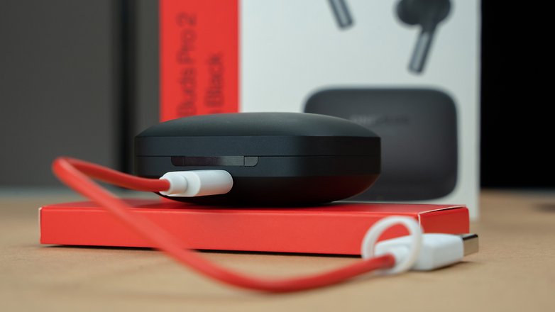 Le boitier de recharge des OnePlus Buds Pro 2 branché à un câble USB-C OnePlus rouge