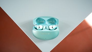 A pair of OnePlus Buds 4 inside their charging case, displayed on a light surface.