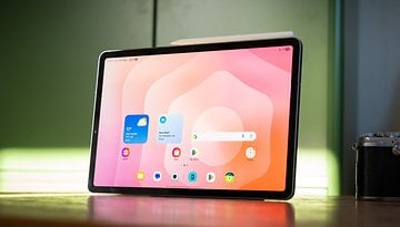 Samsung Galaxy Tab S11 displaying a colorful app interface on a wooden table.