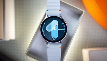 Une Samsung Galaxy Watch 7 présentée dans une boîte avec un bracelet bleu et blanc affichant un cadran numérique.