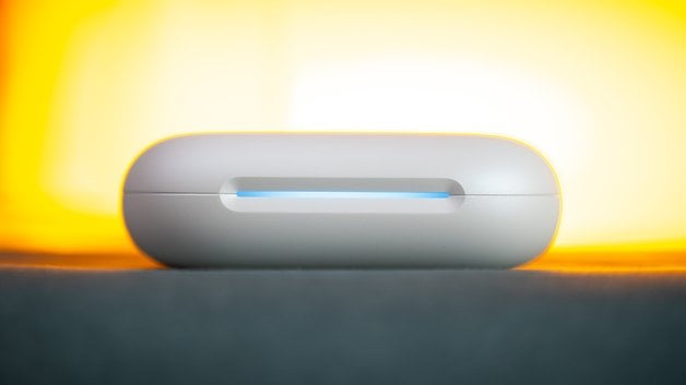 Un boîtier de chargement blanc pour les écouteurs Soundcore Aerofit 2, illuminé par un arrière-plan jaune doux.