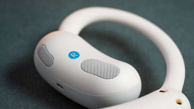 Gros plan sur les écouteurs sans fil Soundcore Aerofit 2, avec un design blanc et un indicateur bleu 'R'.