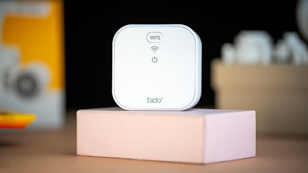 Ein tado°-Gerät auf einer rosa Basis mit sichtbaren WPS- und WLAN-Symbolen.