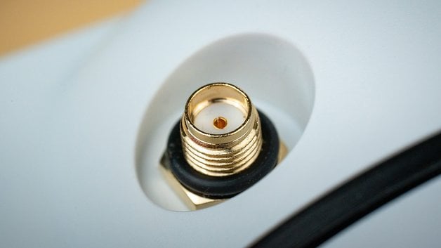 Close-up of a gold-plated coaxial connector on a white surface.