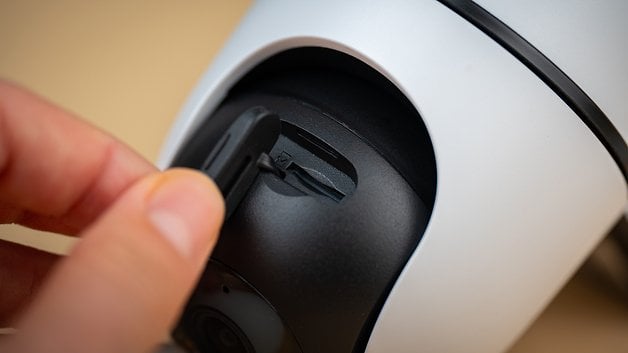 Close up of a hand inserting a microSD card into the Tapo C501 camera.